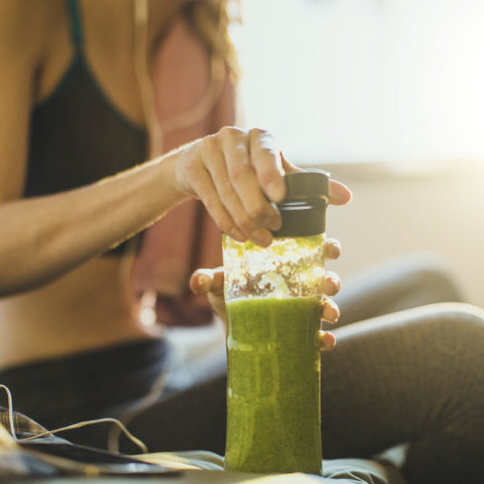 Young woman getting having her green smoothie after training