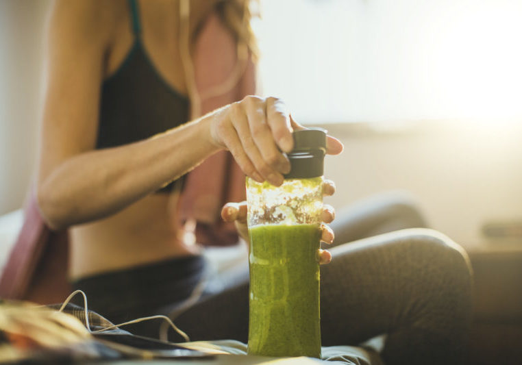 Young woman getting having her green smoothie after training